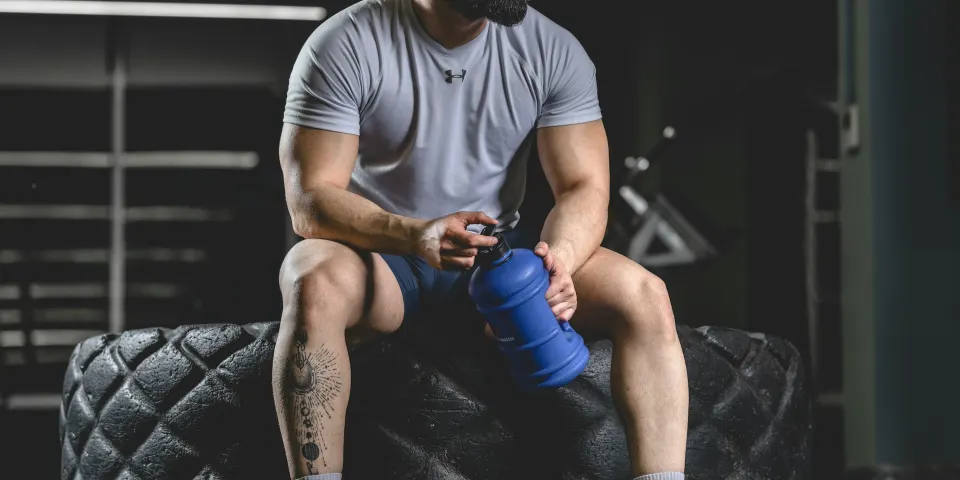 Hombre en el gimnasio sosteniendo un mezclador de batido