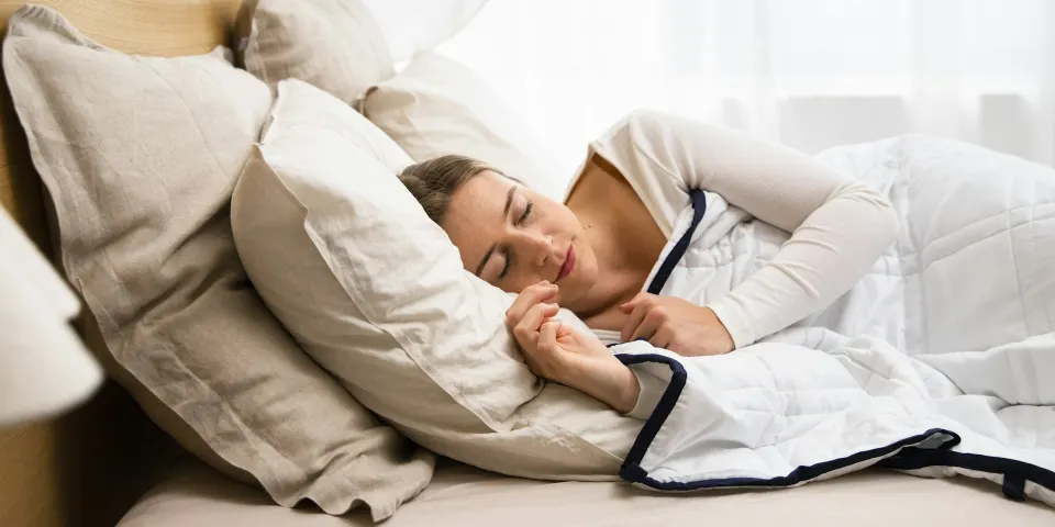 Mujer durmiendo tranquila en una cama con edredón blanco