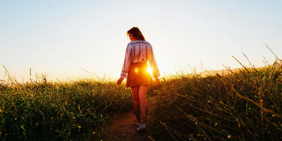 Mujer caminando por un sendero al atardecer