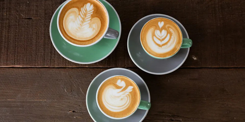 Tres tazas de café con leche sobre una mesa de madera