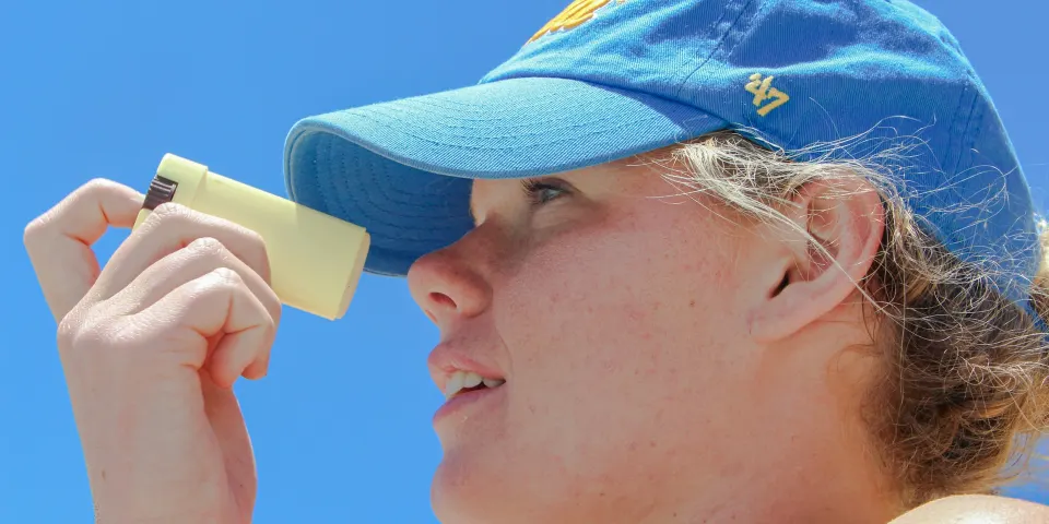 Mujer con gorra aplicándose protector solar bajo el sol