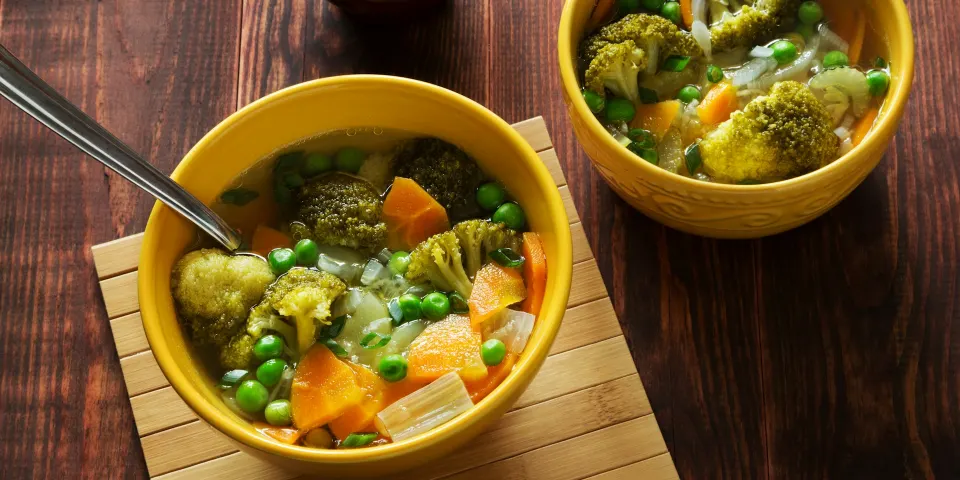 Dos tazones de sopa de verduras con brócoli, arvejas y zanahoria