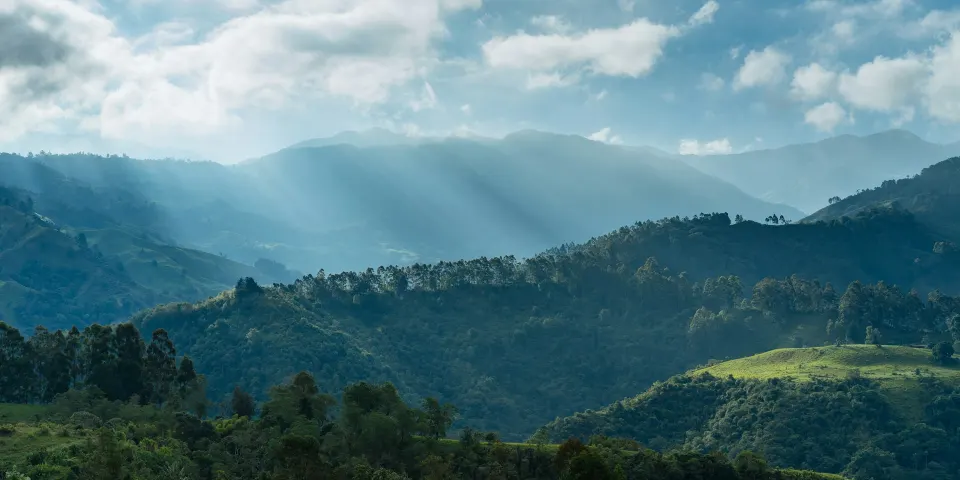 Montañas verdes al amanecer con luz entre las nubes