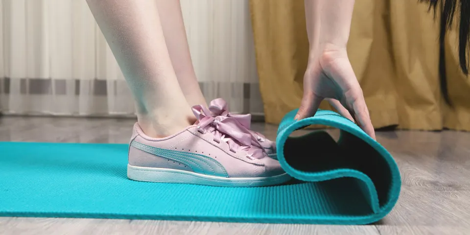 Persona en tenis enrollando un tapete de ejercicio
