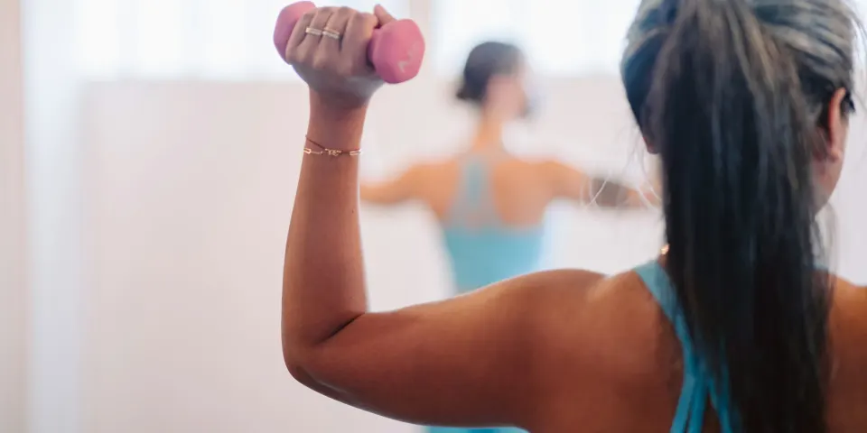 Mujer haciendo ejercicio con mancuernas rosadas