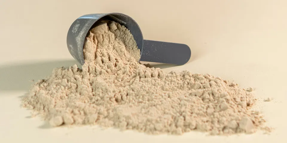 Medidor con proteína en polvo sobre una mesa clara
